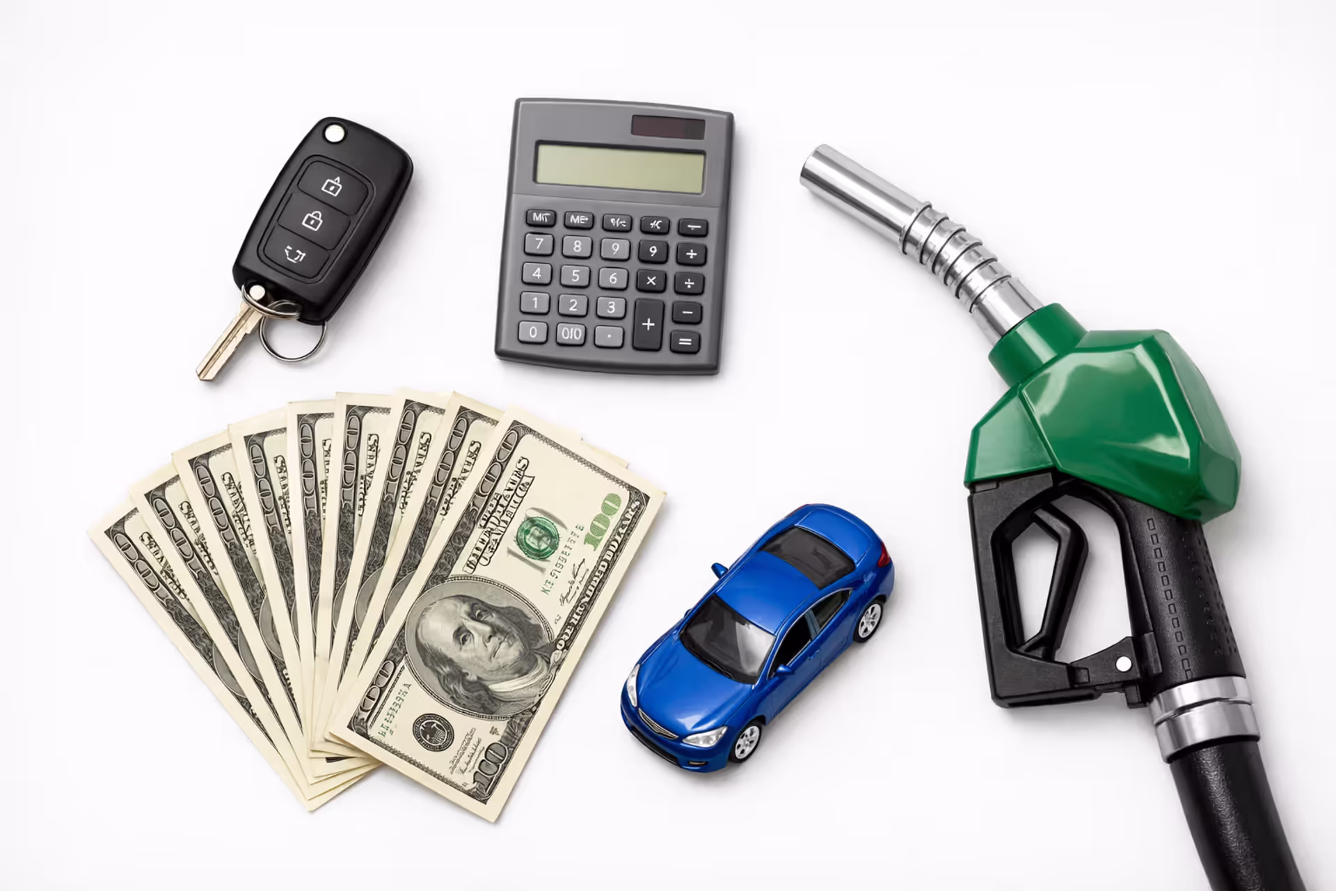 Car key, calculator, US dollar bills, toy car, and fuel nozzle on white desk representing cost per mile driving calculation